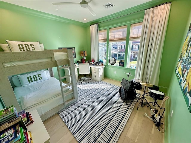 bedroom with wood finished floors, visible vents, and ceiling fan