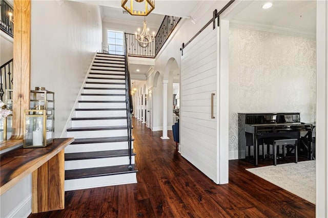 entryway with arched walkways, stairway, wood finished floors, and ornamental molding