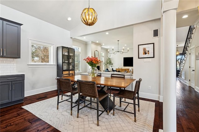 dining area featuring a chandelier, visible vents, lofted ceiling, and wood finished floors