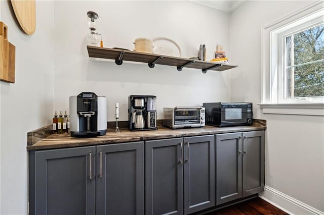 bar featuring baseboards, a toaster, dark wood-style flooring, black microwave, and a dry bar