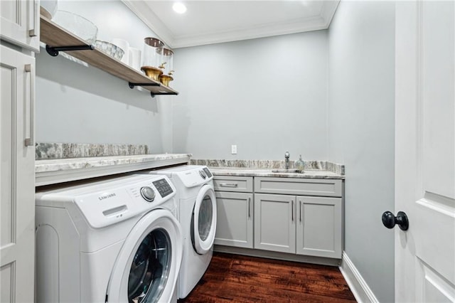 clothes washing area featuring washing machine and clothes dryer, dark wood finished floors, ornamental molding, cabinet space, and a sink