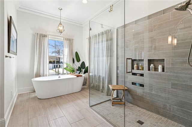 bathroom featuring a freestanding tub, baseboards, crown molding, and a tile shower