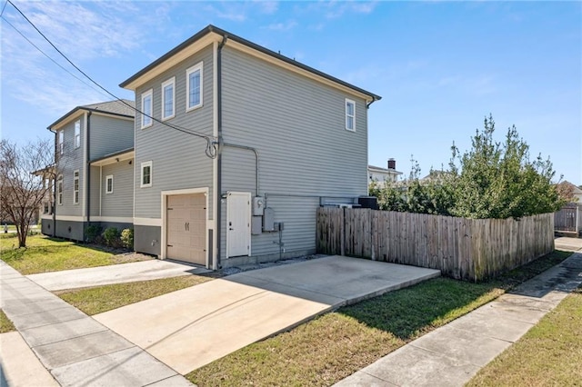 view of property exterior featuring an attached garage, fence, and driveway