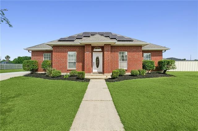 view of front of house with brick siding, solar panels, a front lawn, and fence