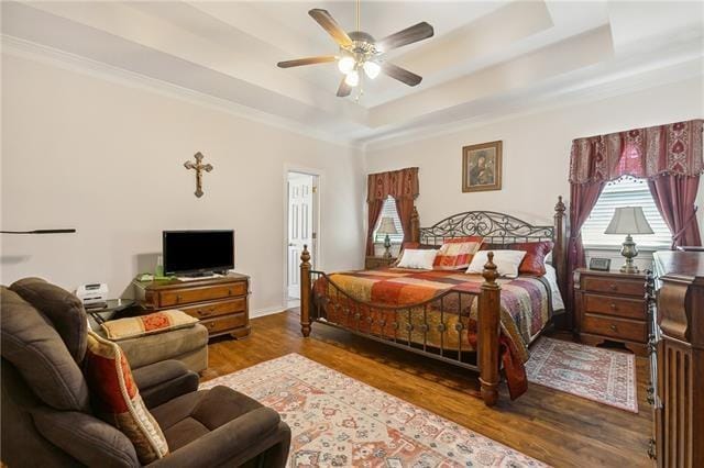 bedroom featuring a ceiling fan, a raised ceiling, and wood finished floors