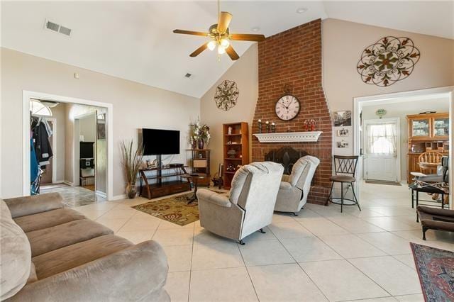 living room with light tile patterned floors, a ceiling fan, visible vents, high vaulted ceiling, and a brick fireplace