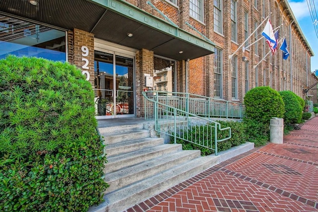 doorway to property featuring covered porch and brick siding