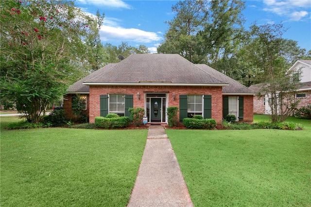 view of front facade with brick siding, a front yard, and roof with shingles