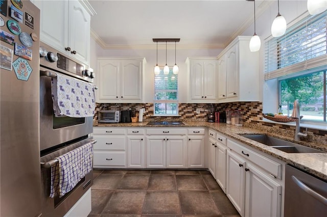 kitchen featuring tasteful backsplash, light stone countertops, stainless steel appliances, white cabinetry, and a sink