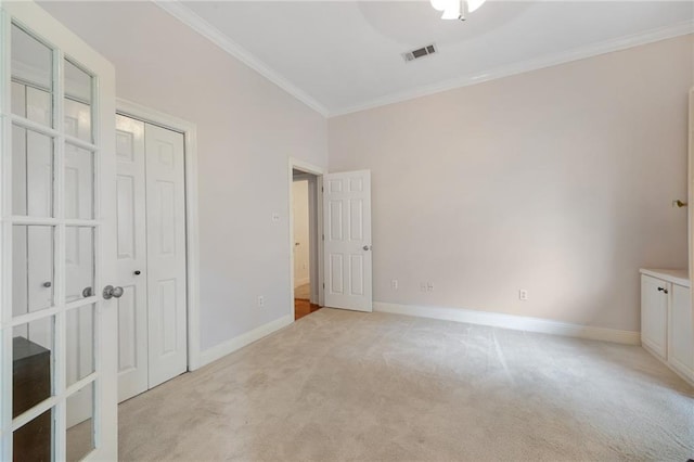 unfurnished bedroom featuring visible vents, baseboards, light colored carpet, ornamental molding, and a closet