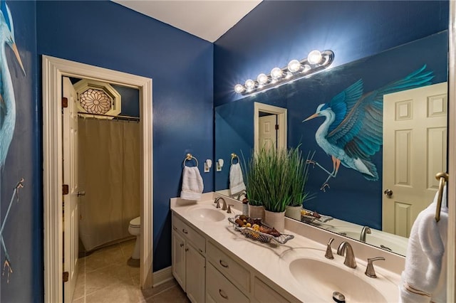 bathroom featuring tile patterned flooring, double vanity, toilet, and a sink