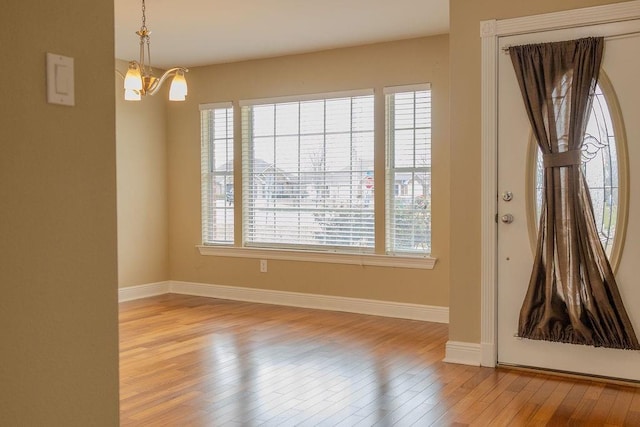 interior space with baseboards, light wood-style floors, and a chandelier