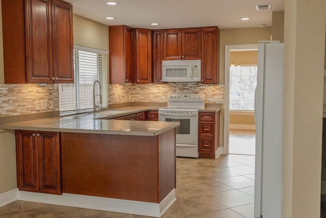 kitchen with white appliances, a healthy amount of sunlight, visible vents, and a peninsula