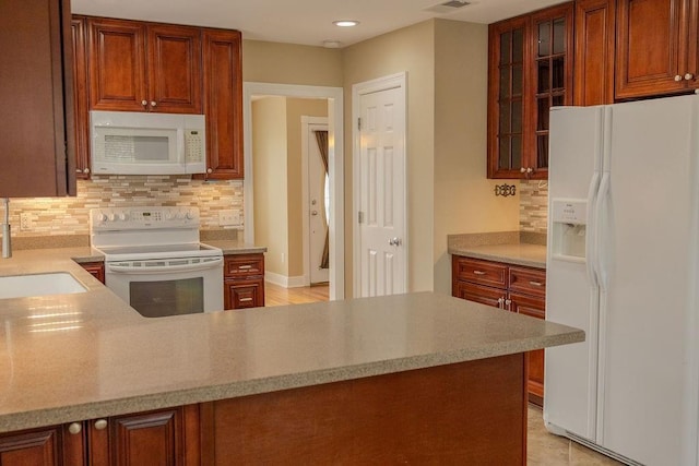 kitchen featuring glass insert cabinets, light countertops, decorative backsplash, white appliances, and a sink