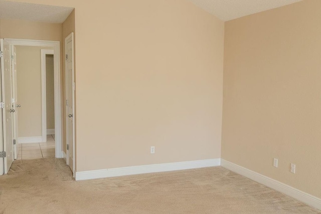 empty room with baseboards and light carpet