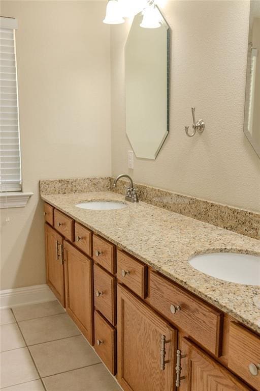 full bathroom featuring double vanity, baseboards, tile patterned floors, and a sink