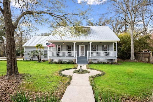 view of front of house with metal roof, covered porch, a front yard, and fence