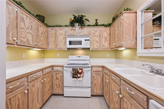 kitchen with a sink, white appliances, light countertops, and light tile patterned floors