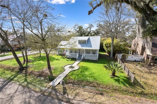 view of front facade featuring a porch, fence, a front yard, and metal roof