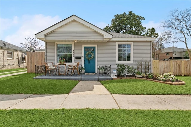 bungalow-style house with a porch, a front lawn, and fence