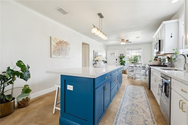 kitchen with blue cabinets, visible vents, a sink, arched walkways, and appliances with stainless steel finishes