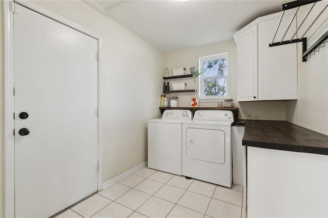 washroom with light tile patterned floors, washing machine and dryer, cabinet space, and a textured ceiling