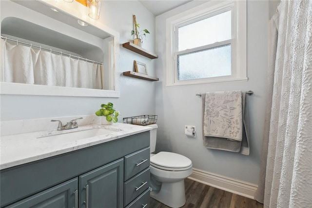 bathroom with vanity, toilet, wood finished floors, and baseboards