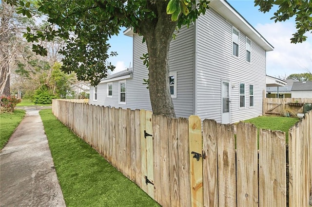 view of side of home featuring a gate, fence private yard, and a lawn