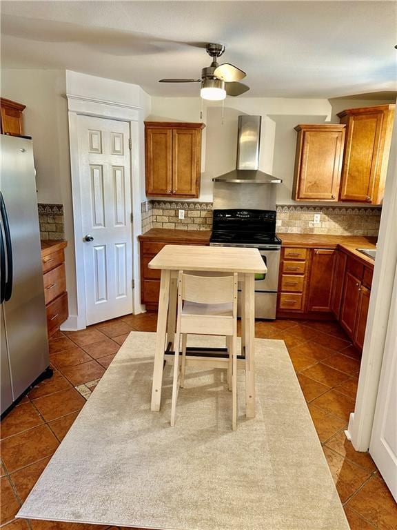 kitchen with backsplash, wall chimney range hood, dark tile patterned floors, and appliances with stainless steel finishes