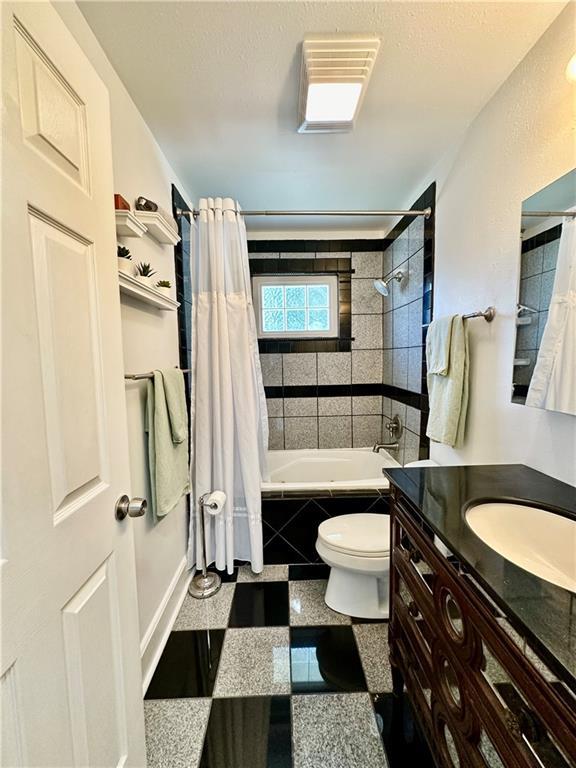 bathroom with vanity, granite finish floor, toilet, and tiled shower / bath