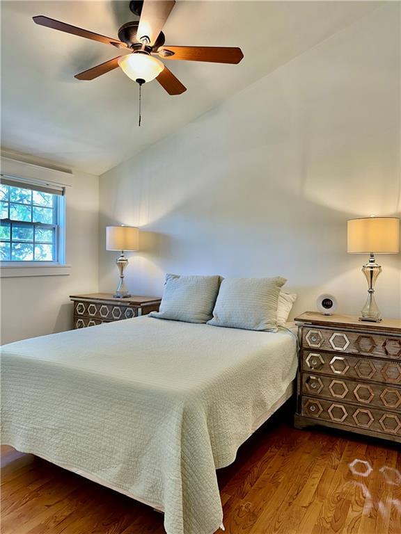 bedroom with wood finished floors, a ceiling fan, and vaulted ceiling