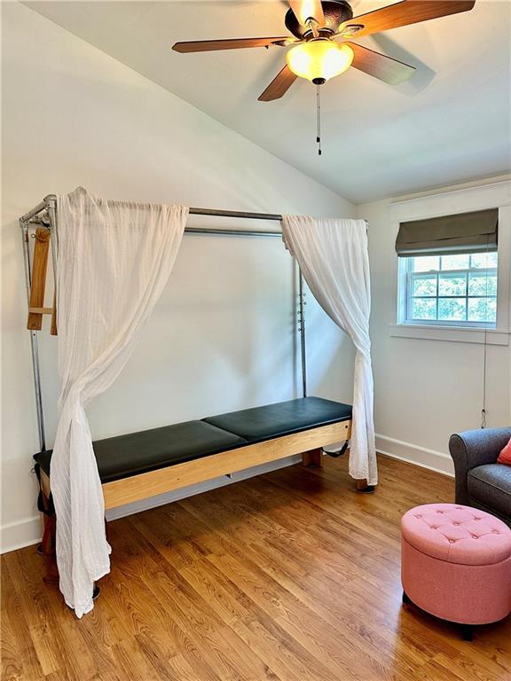 interior space with baseboards, a ceiling fan, lofted ceiling, and wood finished floors