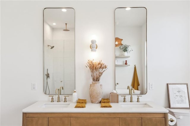 bathroom featuring double vanity, a tile shower, and a sink