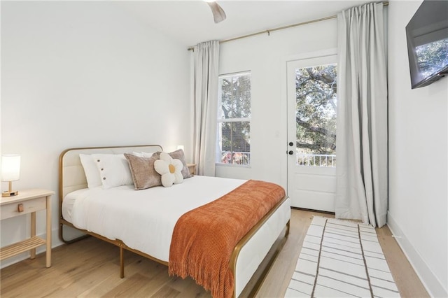 bedroom with baseboards, light wood-style flooring, a ceiling fan, and access to outside