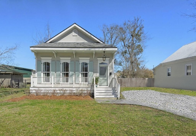 view of front of home with gravel driveway, a porch, a front lawn, and fence