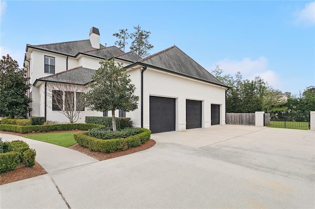 view of front of property with stucco siding, fence, concrete driveway, an attached garage, and a chimney