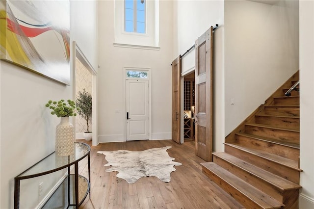 entryway with baseboards, stairway, a barn door, a high ceiling, and hardwood / wood-style flooring