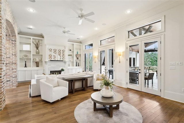 sitting room with hardwood / wood-style floors, baseboards, a fireplace, french doors, and crown molding