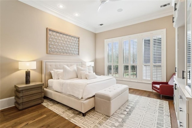 bedroom featuring visible vents, wood finished floors, baseboards, and ornamental molding