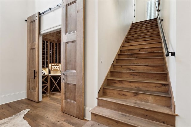 staircase with a barn door and wood finished floors