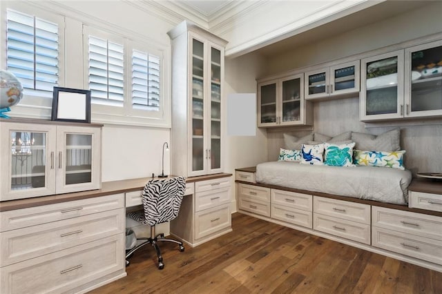 office space featuring dark wood-type flooring, ornamental molding, and built in study area