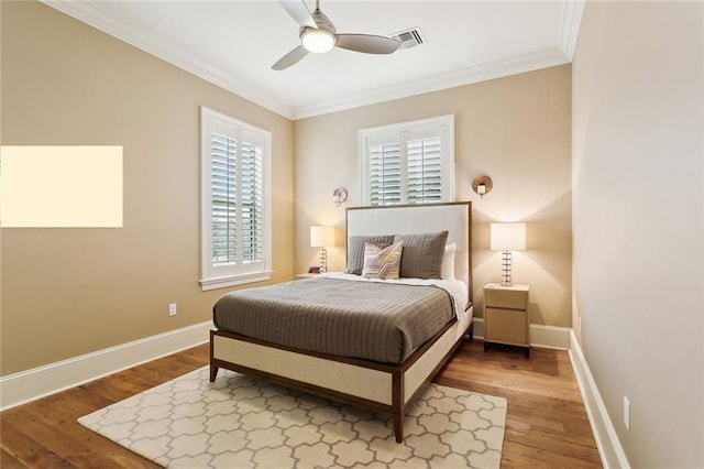 bedroom featuring visible vents, ornamental molding, baseboards, and wood finished floors