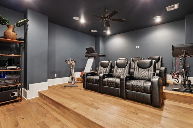 home theater with visible vents, baseboards, hardwood / wood-style floors, and a ceiling fan