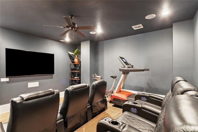 cinema featuring light wood-style flooring, a ceiling fan, visible vents, and baseboards