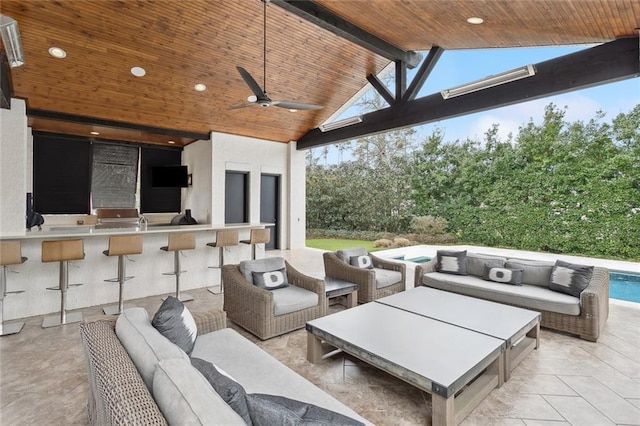 view of patio featuring a ceiling fan, outdoor wet bar, exterior kitchen, an outdoor pool, and an outdoor hangout area