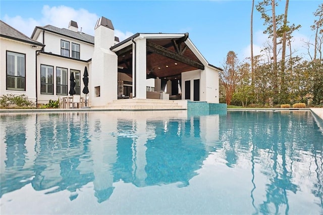 outdoor pool with ceiling fan and a patio area