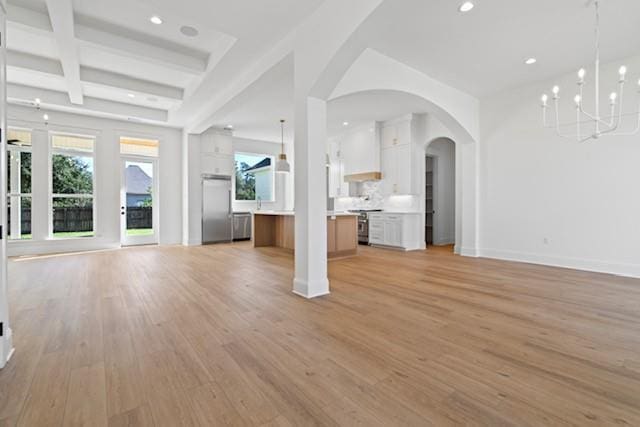 unfurnished living room with beamed ceiling, coffered ceiling, arched walkways, light wood finished floors, and baseboards