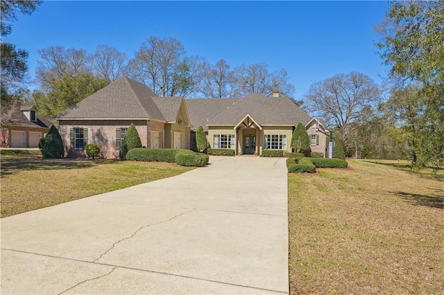 view of front of property with brick siding, an attached garage, concrete driveway, and a front yard