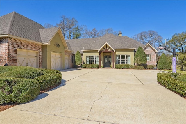 view of front of home featuring a garage, brick siding, concrete driveway, and a shingled roof