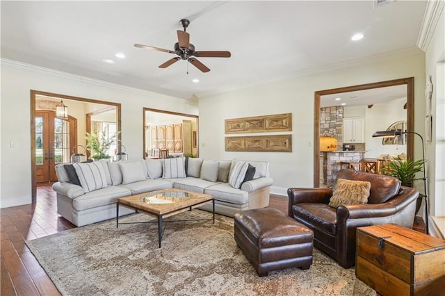 living area with ceiling fan, wood finished floors, baseboards, and ornamental molding